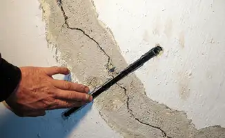 A wall with a large crack is being inspected by a professional in Minneapolis, MN